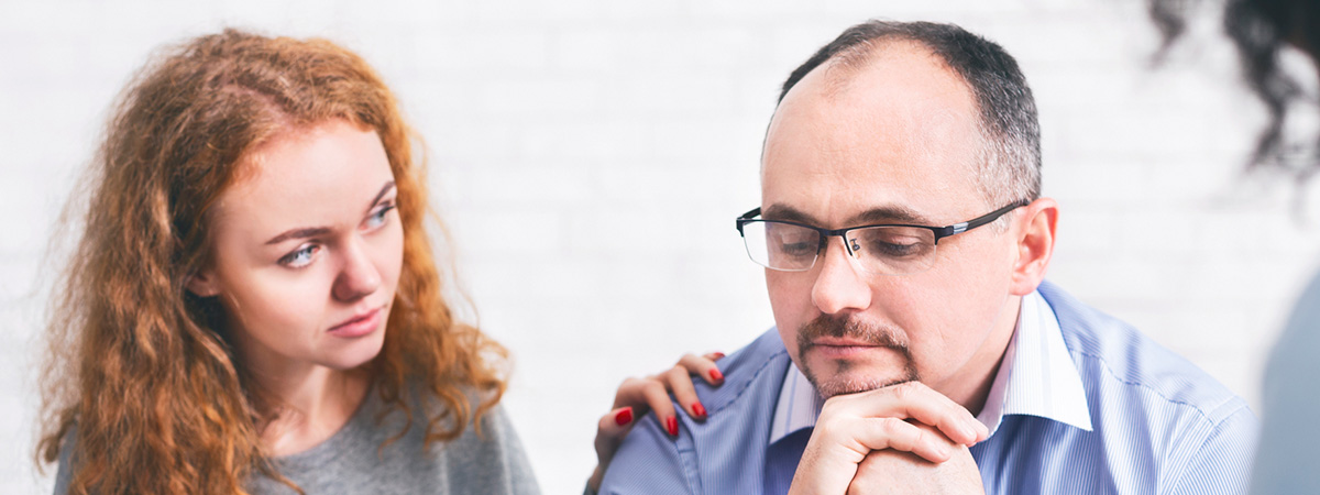  Supportive wife comforting husband with TRD during a meeting with a counselor in Philadelphia.